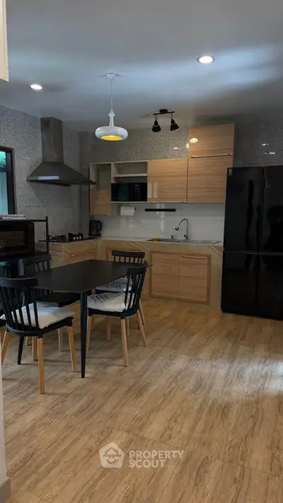 Modern kitchen with wooden flooring, sleek cabinets, and dining area.