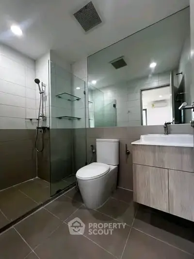 Modern bathroom with glass shower and sleek fixtures in contemporary apartment.