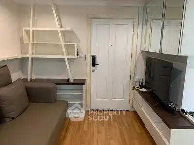 Cozy living room with modern furniture and wooden flooring, featuring a sleek TV setup and stylish shelving.