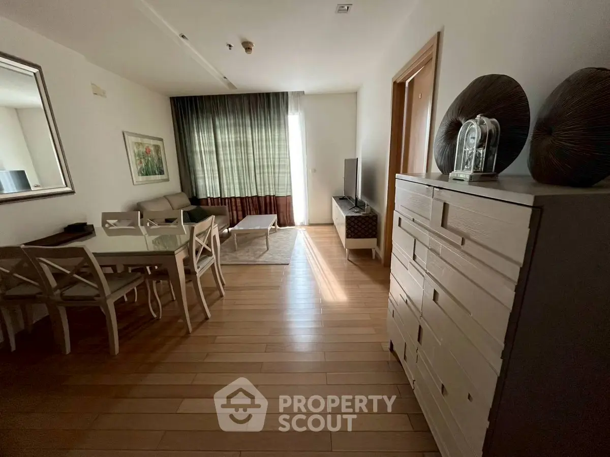 Spacious living room with modern decor and natural light, featuring wooden flooring and stylish furniture.