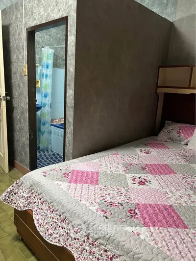 Cozy bedroom with floral quilt and adjacent bathroom in a charming home.