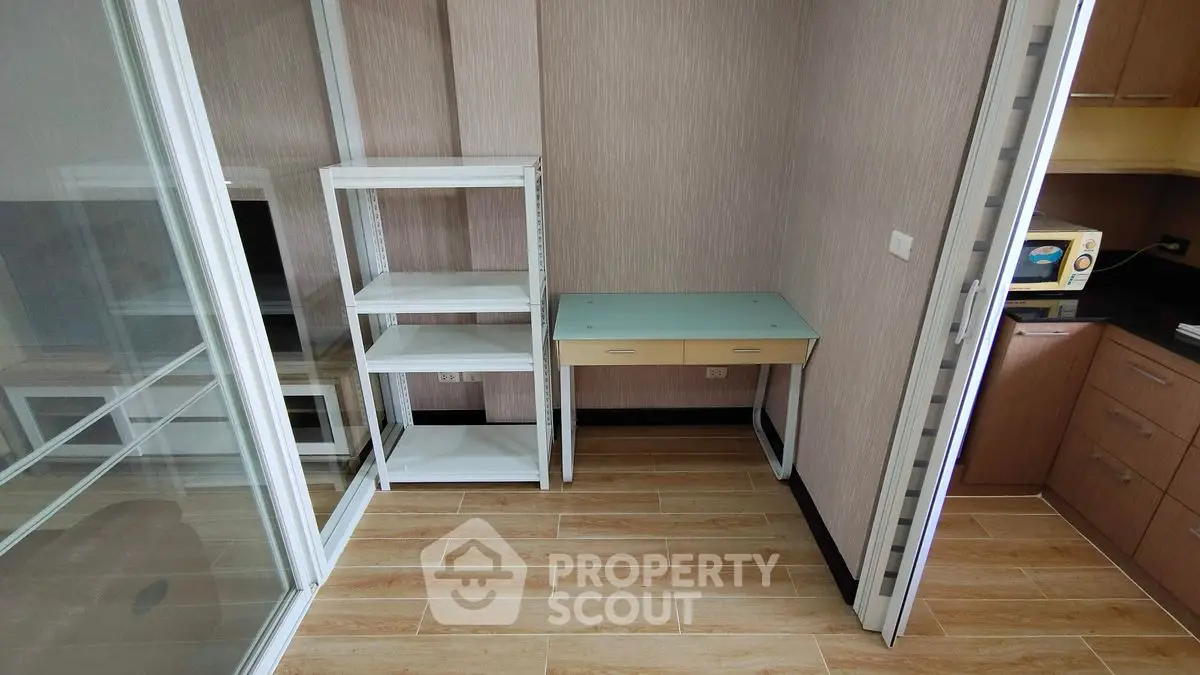 Compact study area with glass desk and shelving, adjacent to modern kitchen.