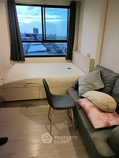 Cozy bedroom with city view, featuring a bed, sofa, and stylish chair.