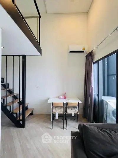 Modern loft apartment with high ceilings, staircase, and large windows for natural light.