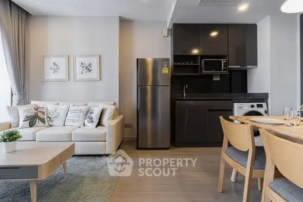 Modern living room with open kitchen, featuring sleek appliances and stylish decor.