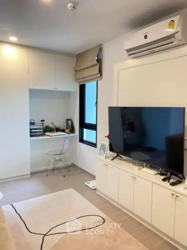 Modern living room with sleek TV setup and cozy workspace corner.