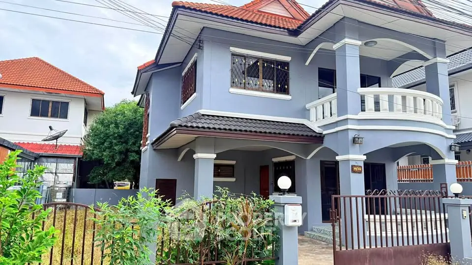 Charming two-story house with elegant balcony and lush garden in a serene neighborhood.