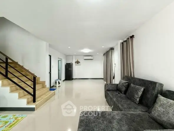 Spacious modern living room with sleek staircase and plush gray sofa in a contemporary home.