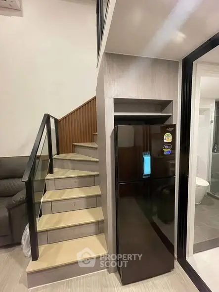 Modern duplex interior with sleek staircase and black refrigerator
