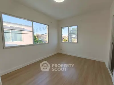 Bright empty room with large windows and wooden flooring, perfect for customization.