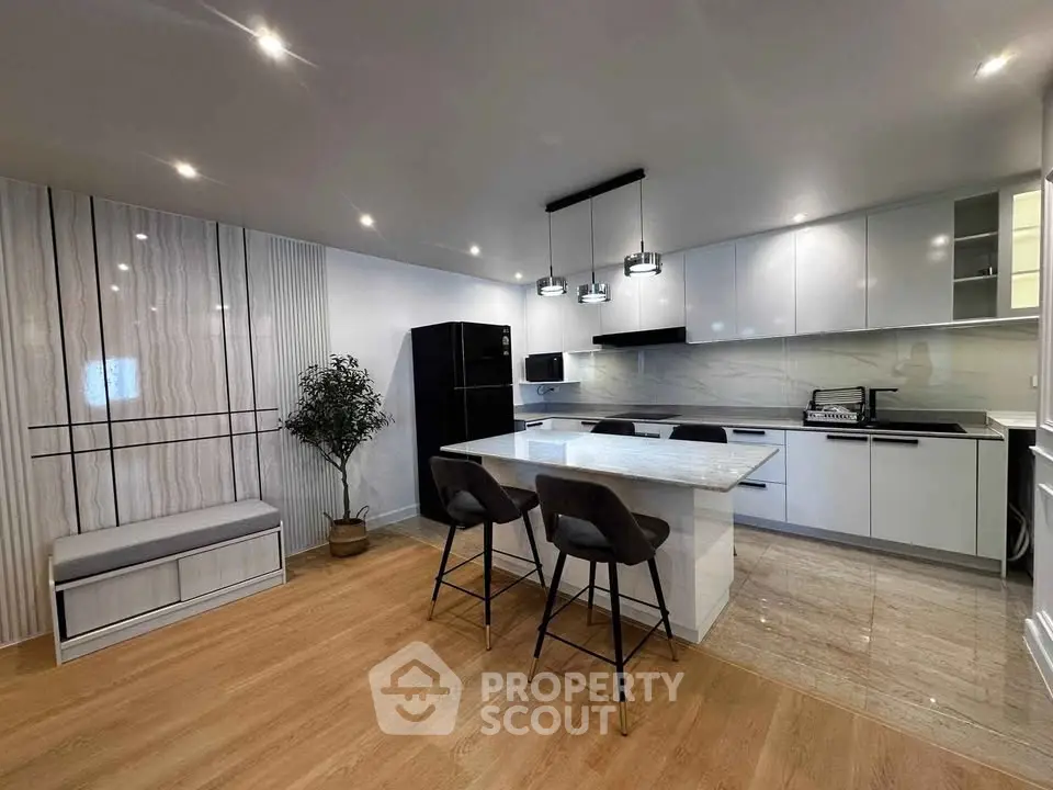 Modern kitchen with sleek design, featuring an island, contemporary lighting, and integrated appliances.