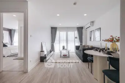 Modern living room with stylish decor and open layout leading to a cozy bedroom.
