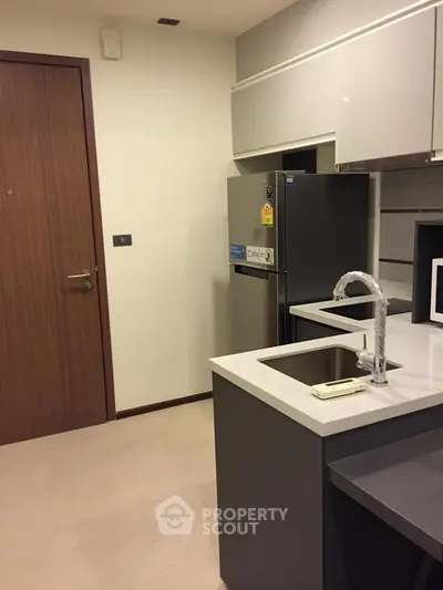 Modern kitchen with sleek cabinetry and stainless steel appliances in a stylish apartment.