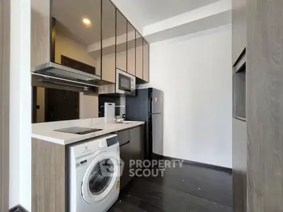Modern kitchen with sleek appliances and washing machine in compact layout