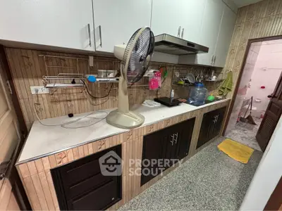 Spacious kitchen with modern cabinetry and fan, featuring a closed layout and ample storage.