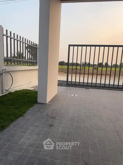 Modern gated entrance with tiled flooring and scenic view of open fields.