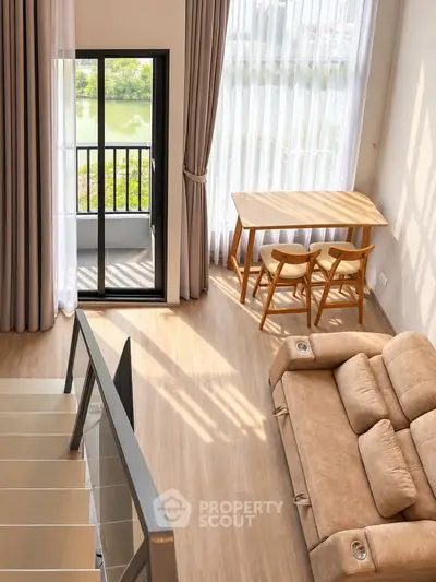 Spacious living room with large windows and balcony view, featuring modern furniture and natural light.