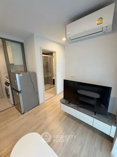 Modern apartment interior with air conditioning, TV, and kitchen appliances, showcasing sleek design and functionality.