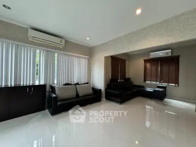 Spacious modern living room with sleek black sofas and large windows for natural light.