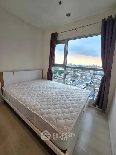 Spacious bedroom with large window offering stunning city views, perfect for relaxation and comfort.