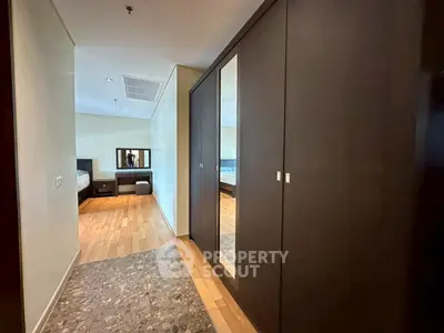 Spacious bedroom with mirrored wardrobe and elegant wooden flooring