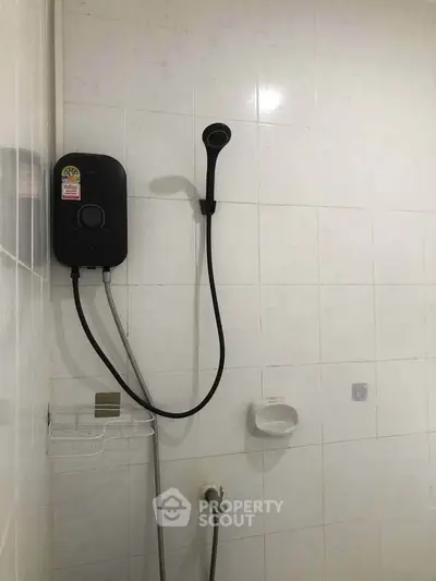 Minimalist bathroom with wall-mounted shower and white tiles, perfect for modern living.