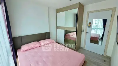 Cozy bedroom with pink bedding and mirrored wardrobe in modern apartment
