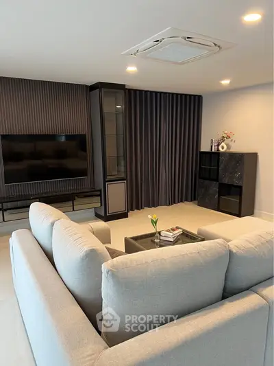 Modern living room with sleek design, featuring a large sofa, flat-screen TV, and elegant decor.
