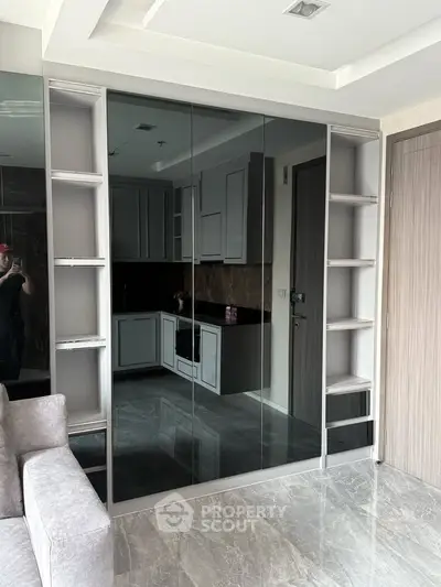 Modern apartment interior with sleek kitchen and mirrored storage, featuring elegant marble flooring.