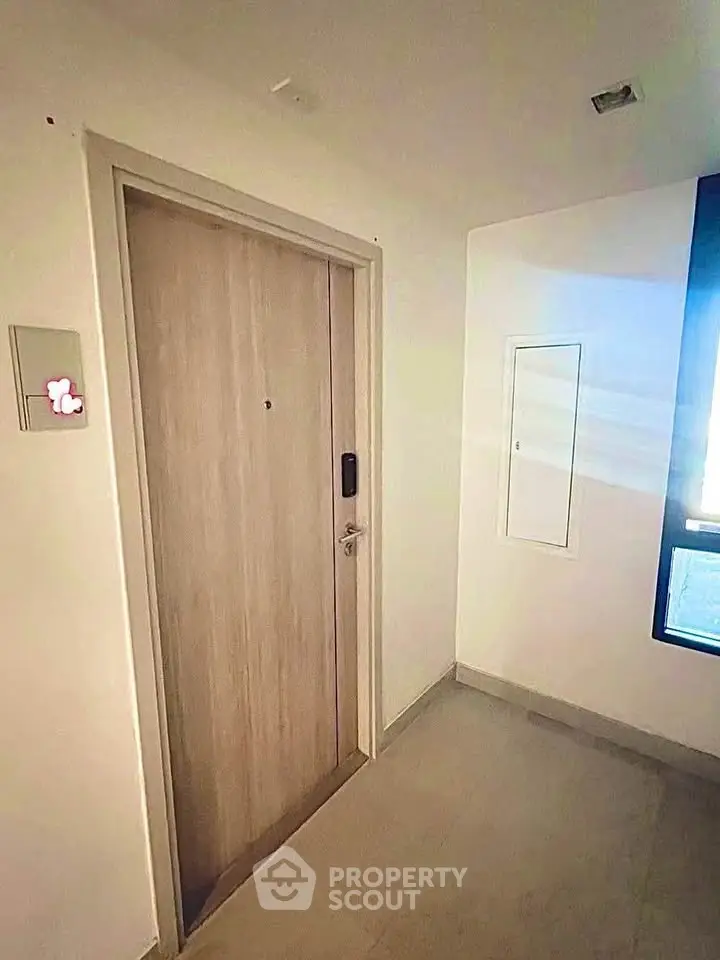 Modern apartment entrance with secure door and sleek design in a well-lit hallway.