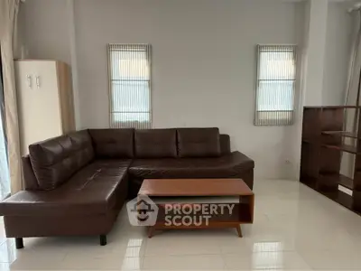 Spacious living room with modern brown leather sectional sofa and wooden coffee table.