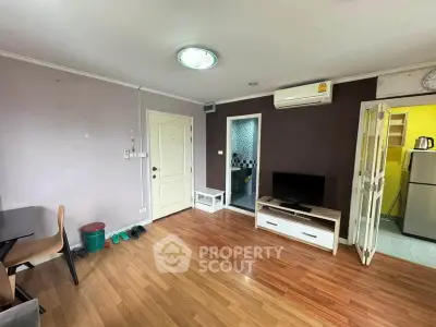 Cozy living room with wooden flooring, TV unit, and air conditioning in a modern apartment.