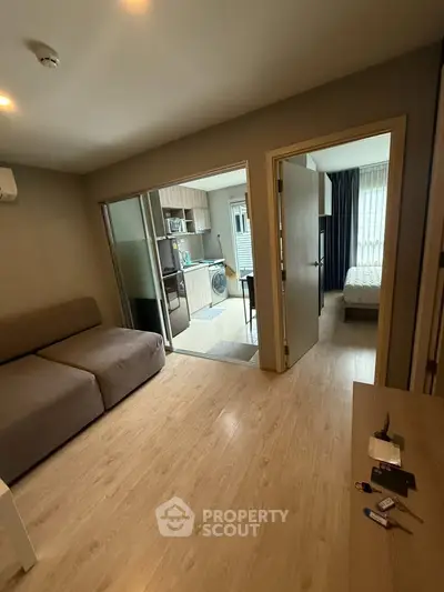 Modern apartment interior with cozy living room, kitchen, and bedroom, featuring wooden flooring and sleek design.
