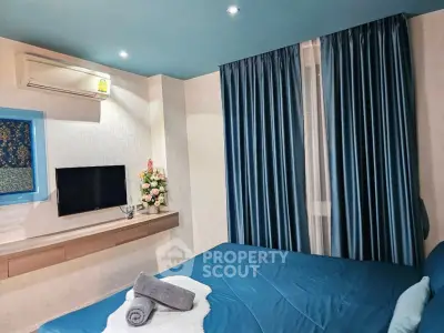 Modern bedroom with blue accents, featuring a wall-mounted TV and air conditioning.