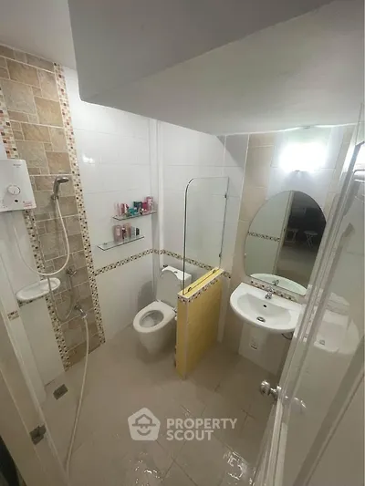 Compact bathroom with modern shower and sleek fixtures in a cozy real estate unit.