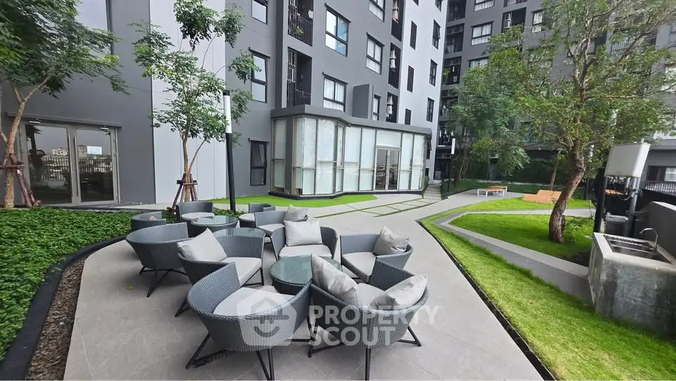 Modern apartment building with stylish outdoor seating area and lush greenery.