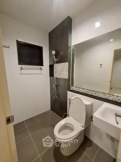 Modern bathroom with sleek design, featuring a shower, toilet, and stylish tile accents.