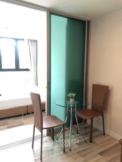 Modern apartment with stylish dining area and glass table, featuring elegant chairs and natural light.