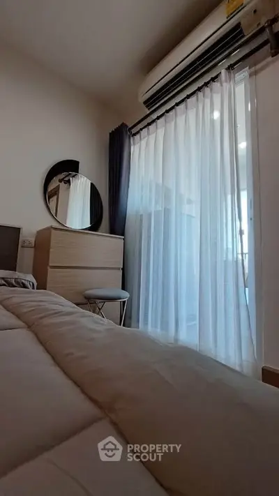 Cozy bedroom with modern decor and natural light from large window.