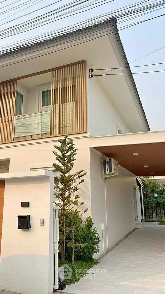 Modern two-story house with sleek design and wooden accents, featuring a spacious driveway and lush greenery.