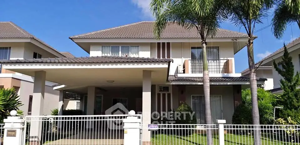 Charming two-story house with a spacious carport and lush garden, perfect for family living.