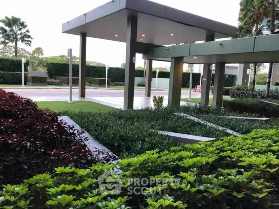 Modern building entrance with lush landscaping and sleek architectural design.
