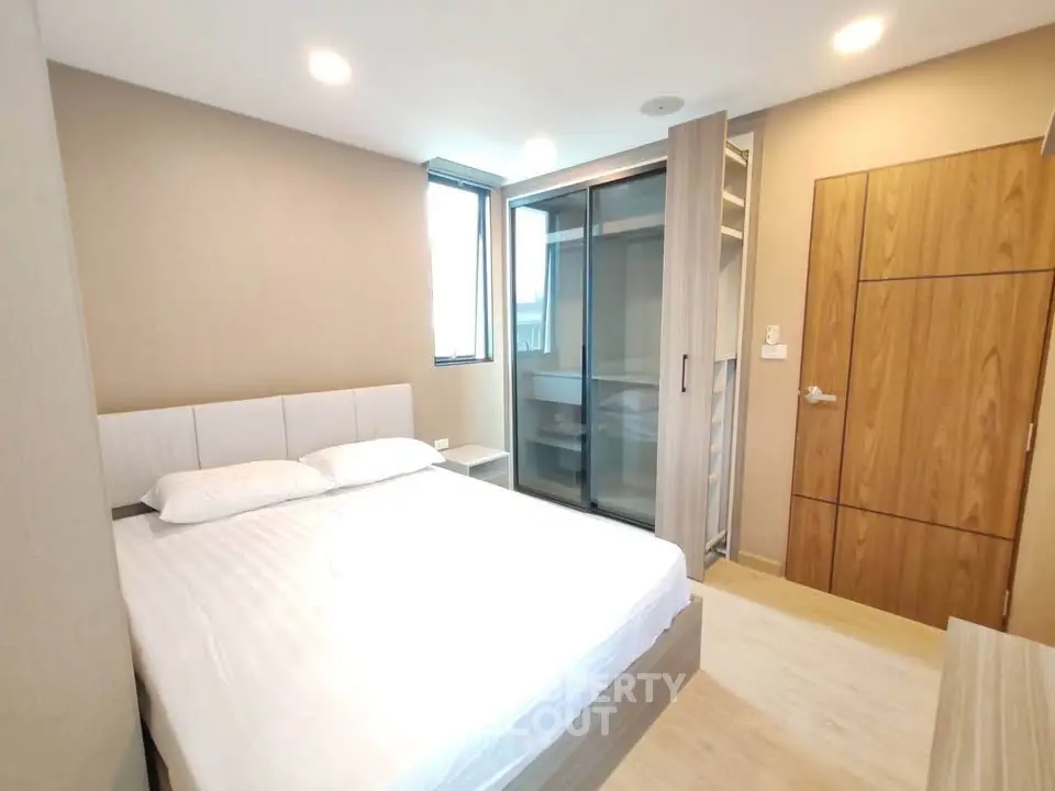 Modern bedroom with sleek design and ample natural light, featuring a comfortable bed and stylish wardrobe.