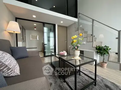 Modern living room with stylish decor and mezzanine level, featuring glass railing and cozy seating area.