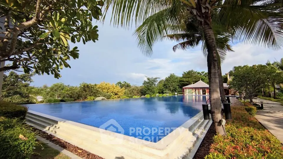 Stunning infinity pool with lush tropical surroundings and clear blue skies.