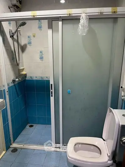 Compact bathroom with blue tiles and sliding glass shower door