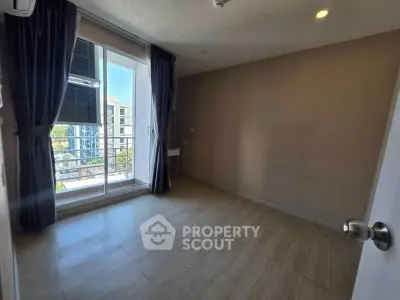Spacious bedroom with large window and balcony access in modern apartment.