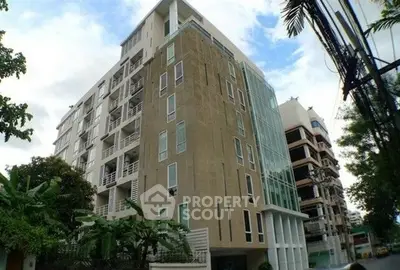 Modern apartment building with glass facade and balconies in urban setting.