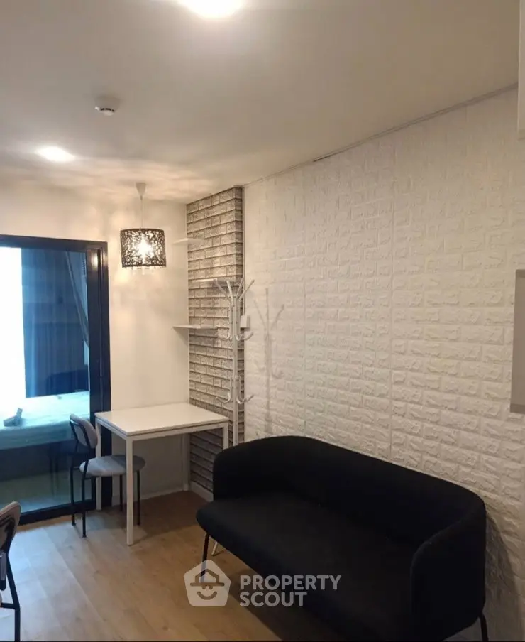 Modern living room with stylish black sofa and dining area, featuring elegant lighting and textured walls.