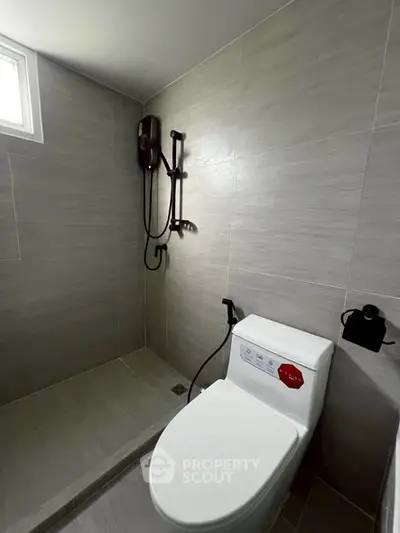 Modern bathroom with sleek shower and toilet in a minimalist design.